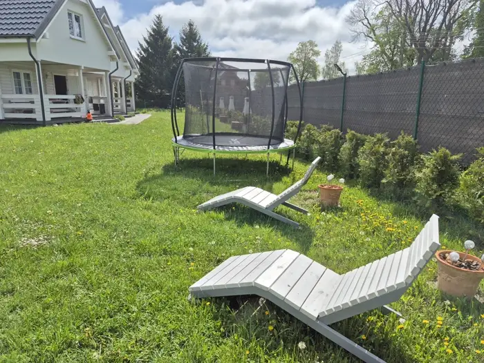 Trampolina i leżaki w ogrodzie w słoneczny dzień